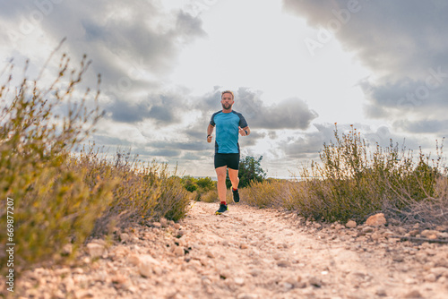middle-aged man running on dirt road under cloudy sky