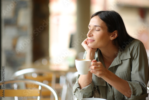 Woman relaxing drinking coffee in a terrace photo