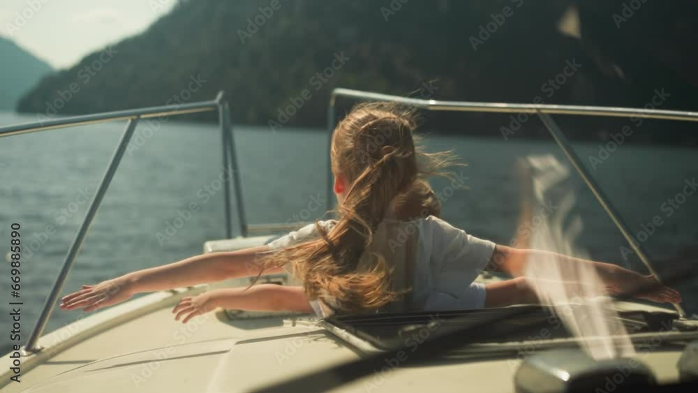 Calm girl and boy straighten arms to sides sailing on motorboat on sea on sunny day. Siblings relax enjoying stunning view in summer. Observing beauty of nature