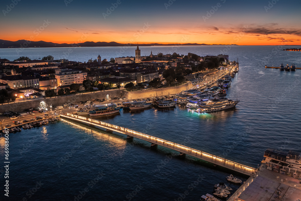 Zadar, Croatia - Aerial view of the old town of Zadar at golden sunset sky with illuminated City Bridge (Gradski most), Cathedral of St. Anastasia tower and yacht marina