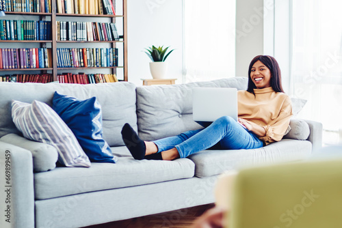 cheerful african american hipster girl satisfied with resting at modern interior living room