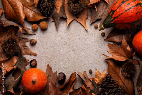 Beautiful autumn composition. Fall dried brown leafs, pumpkins, nuts, pine cones, chestnuts frame. Natural colours. Beige background. Copy space.