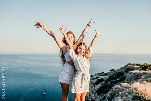Sea family vacation together, happy mom and teenage daughter hugging and smiling together over sunset sea view. Beautiful woman with long hair relaxing with her child. Concept of happy friendly family