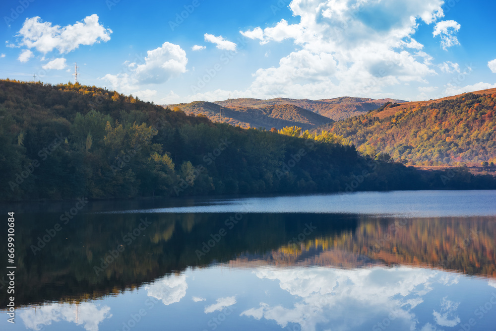mountainous autumn landscape with lake. nature background with trees on the shore reflecting in the calm water. warm sunny weather in the morning