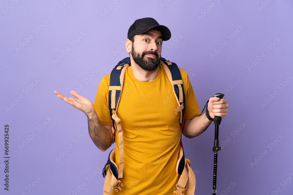 Caucasian handsome man with backpack and trekking poles over isolated background making doubts gesture Caucasian handsome man with backpack and trekking poles over isolated background making doubts gesture
