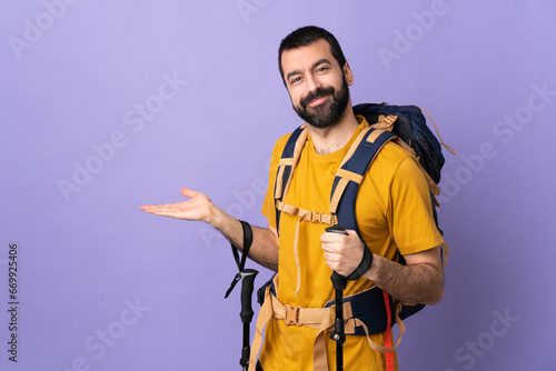 Caucasian handsome man with backpack and trekking poles over isolated background extending hands to the side for inviting to come