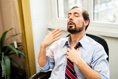 Foto Nervous businessman working in a very hot office, he is sweating and loosening h