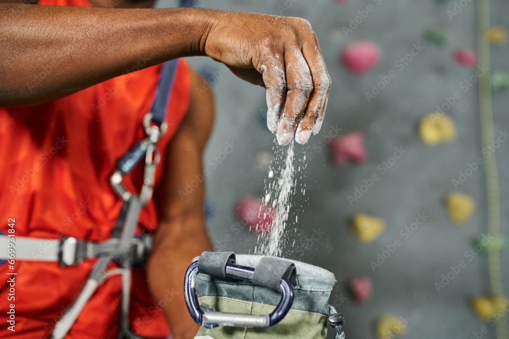 cropped view of hand of young african american man using talc powder on his equipment, bouldering