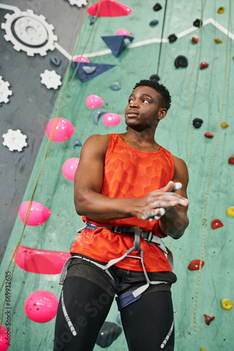 vertical shot of handsome african american man using talc powder with rock wall on backdrop