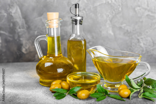Olive oil in a bottle on texture background. Oil bottle and a bowl with branches and fruits of olives. Place for text. copy space. cooking oil and salad dressing.