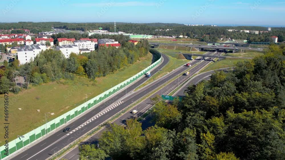 Aerial perspective of a bustling highway intersection surrounded by greenery and urban structures - Gdynia Wielki Kack Aerial perspective of a bustling highway intersection surrounded by greenery and urban structures - Gdynia Wielki Kack