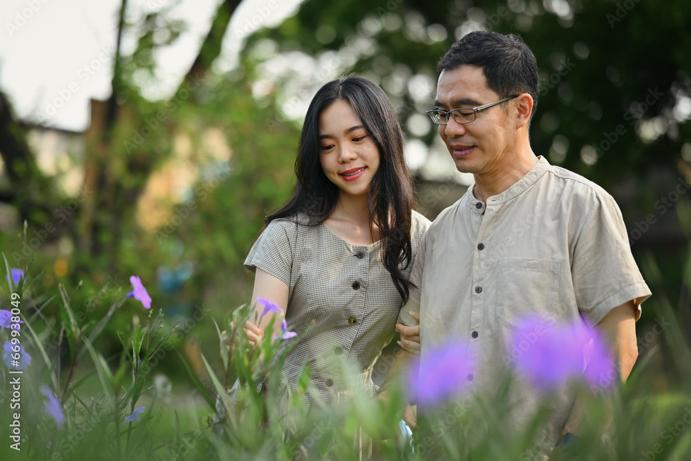 Happy middle age man and daughter admiring view of plants and wild flowers on beautiful day Happy middle age man and daughter admiring view of plants and wild flowers on beautiful day