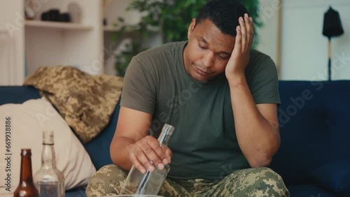 Depressed war veteran drinking alcohol from bottle in room, substance abuse photo