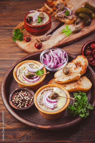 Fresh homemade chicken liver pate in ceramic bowls and appetizers on rustic background