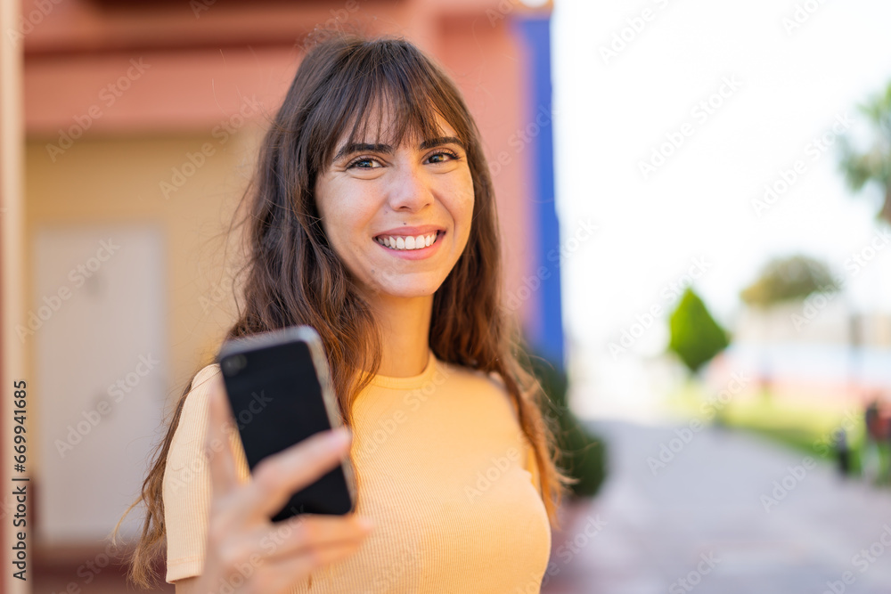 Young woman using mobile phone at outdoors with happy expression Young woman using mobile phone at outdoors with happy expression