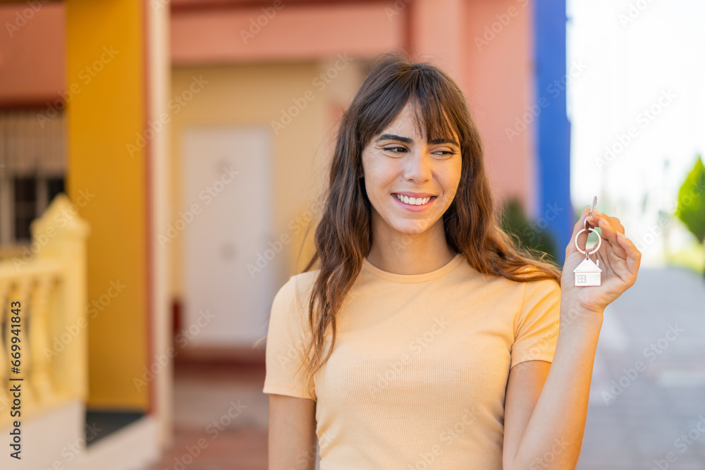 Young woman holding home keys at outdoors with happy expression Young woman holding home keys at outdoors with happy expression