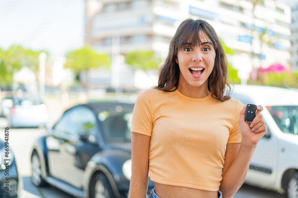 Young woman holding car keys at outdoors with surprise and shocked facial expression