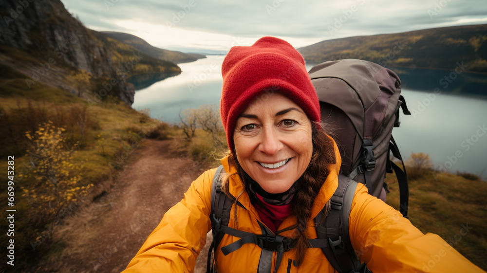 Mature woman with backpack taking selfie on hiking trip