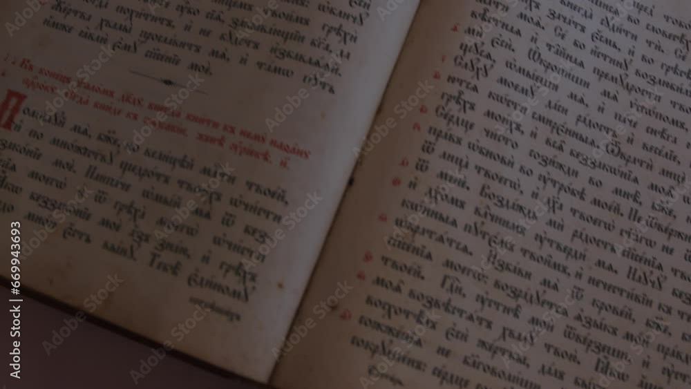 Slider shot over pages with candle wax stains of old antique religious book. Orthodox, psalter, 19th century, prayers and psalms. Cyrillic Church Slavonic font. History, archives and research concept Slider shot over pages with candle wax stains of old antique religious book. Orthodox, psalter, 19th century, prayers and psalms. Cyrillic Church Slavonic font. History, archives and research concept