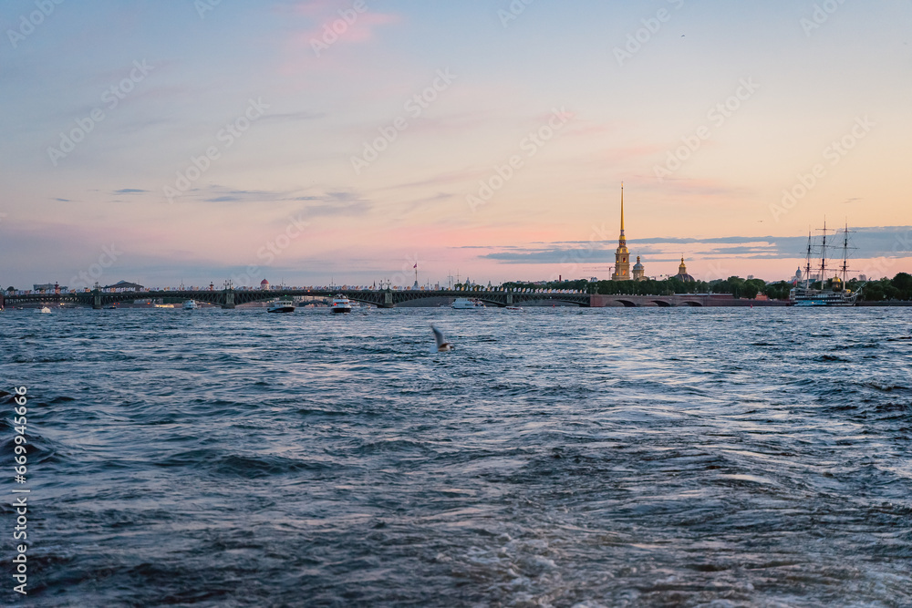 view from the Neva River to the center of St. Petersburg Trinity Bridge and Peter and Paul Cathedral against the sunset sky