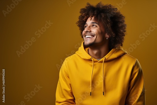 Curly-haired male hipster freelancer in hoodie smiling studio photo