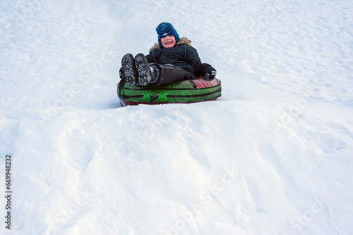 child boy riding on snow tubing downhill. Winter joy and outdoor activity