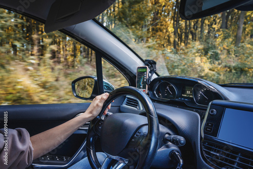 Female hands on the steering wheel of a car. Woman driving a car on country road.. Auto travel concept