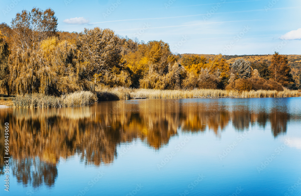 Beautiful autumn landscape. Lake with reflections of yellow autumn forest on a sunny day