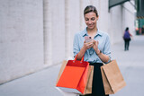  happy hipster girl with shopping packages messaging with friend via smartphone