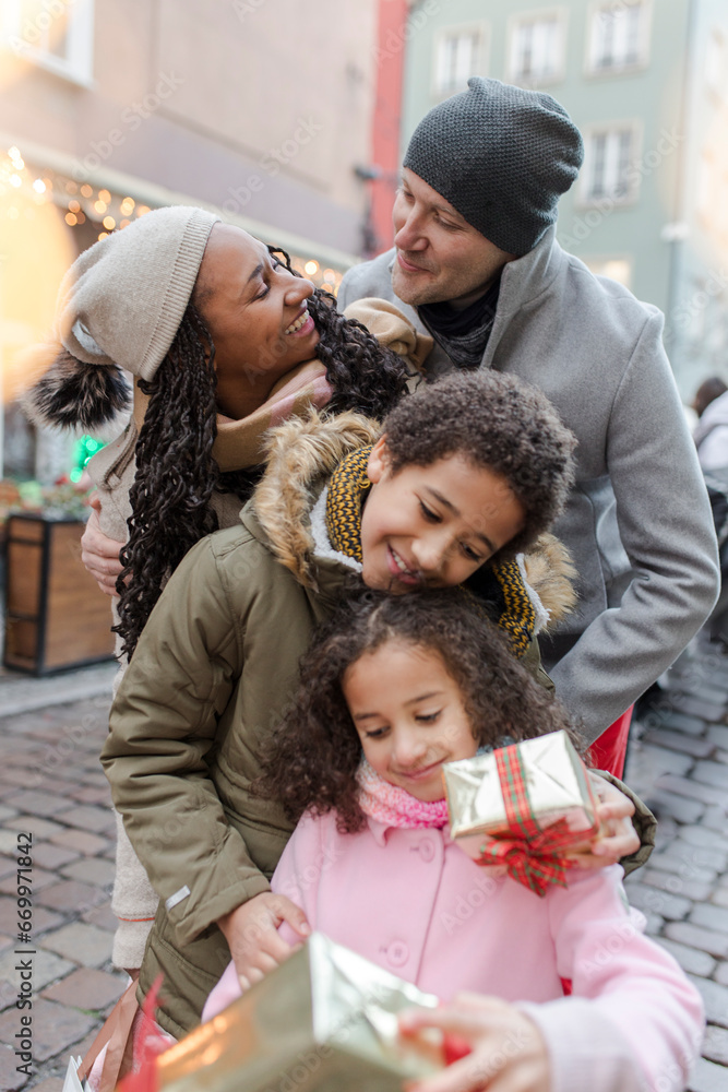 Happy parents with children holding gift boxes at Christmas market Happy parents with children holding gift boxes at Christmas market