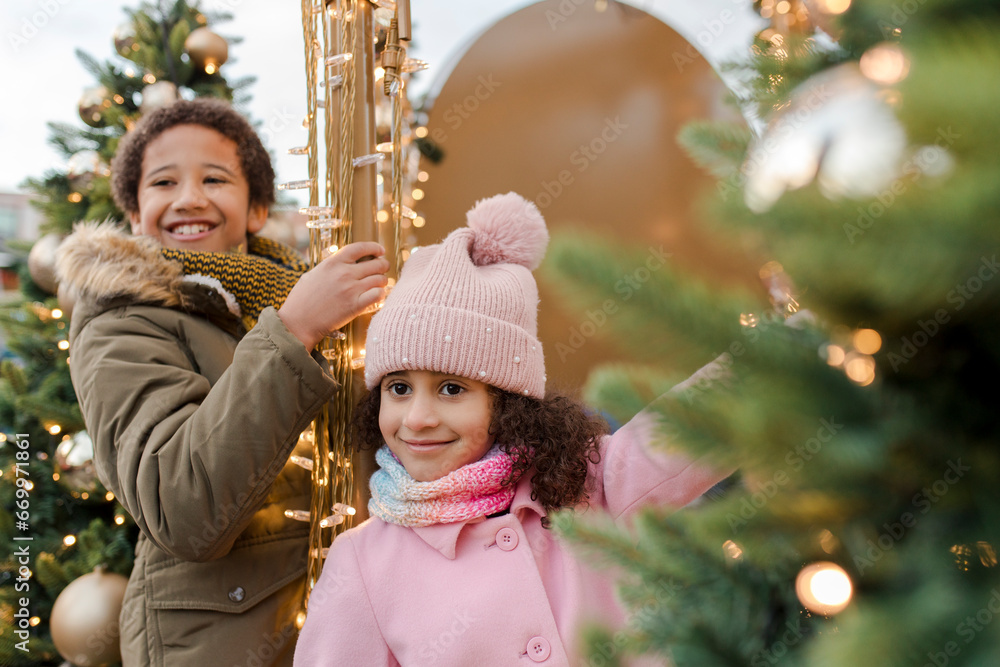 Happy brother and sister enjoying near Christmas trees Happy brother and sister enjoying near Christmas trees