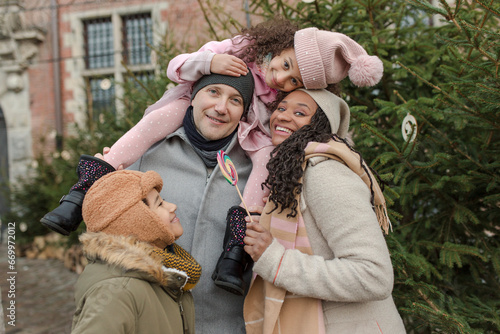 Happy family embracing and having fun together near Christmas tree photo