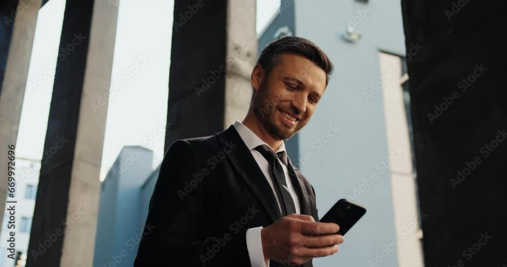 Middle-aged businessman standing outside, in front of camera and smiling. Middle-aged businessman standing outside, in front of camera and smiling.