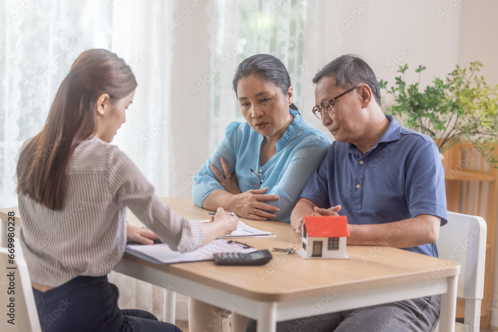 Elderly couples satisfying retirement home purchase with contract and key handover from a saleswoman Elderly couples satisfying retirement home purchase with contract and key handover from a saleswoman