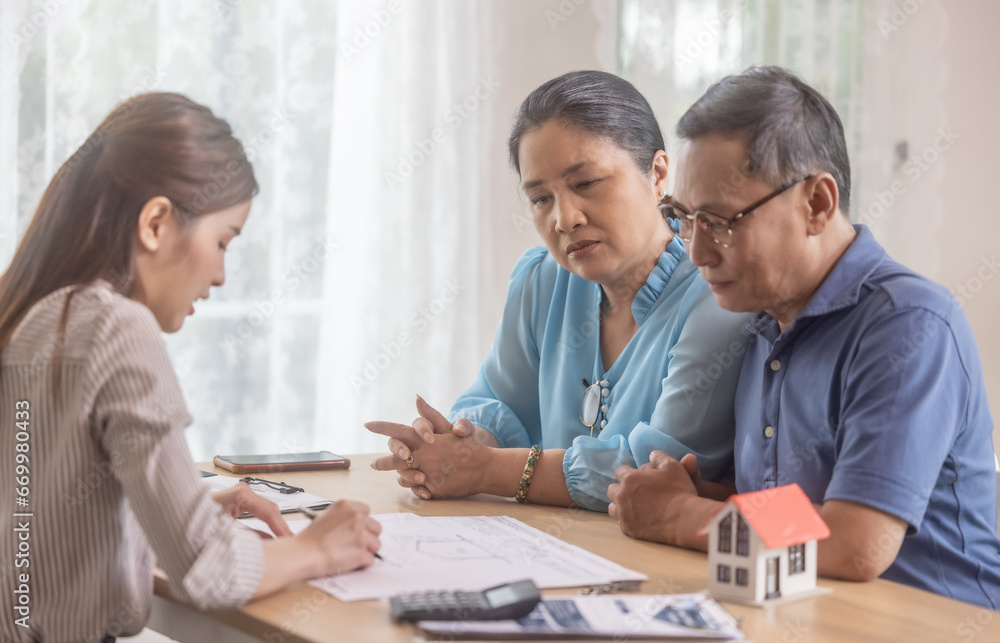Elderly couples satisfying retirement home purchase with contract and key handover from a saleswoman Elderly couples satisfying retirement home purchase with contract and key handover from a saleswoman