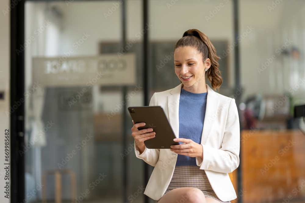 Portrait of a smart businesswoman sitting cross-legged on a chair and holding a digital tablet. Portrait of a smart businesswoman sitting cross-legged on a chair and holding a digital tablet.