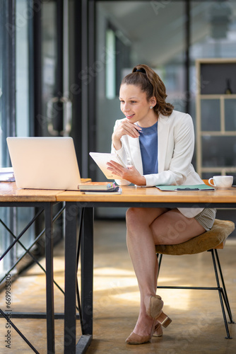 Full-size protrait businesswoman sitting in front of laptop considering work in the office Think about the work concept. Plan a new project