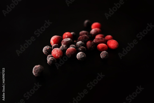 frozen cranberries and black currants on a black background