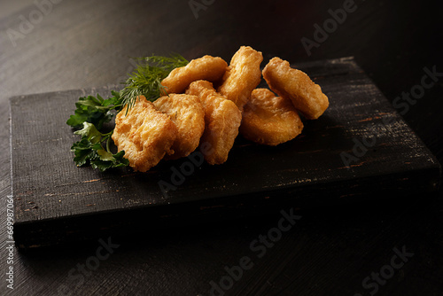 nuggets with green lettuce on a wooden board on a black background