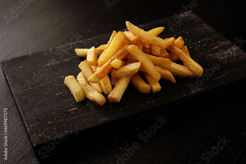 French fries on a wooden board on a black background