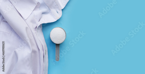 Detergent powder in measuring spoon with cloth before washing. Laundry concept.