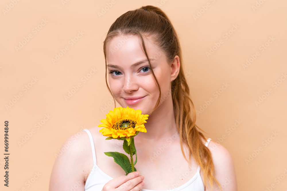 Young caucasian girl isolated on beige background holding a sunflower. Close up portrait Young caucasian girl isolated on beige background holding a sunflower. Close up portrait