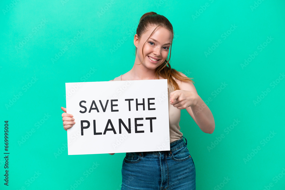 Young caucasian woman isolated on green background holding a placard with text Save the Planet and pointing to the front Young caucasian woman isolated on green background holding a placard with text Save the Planet and pointing to the front