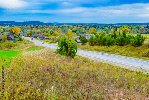 autumn landscape with a top view of the village, road and passing car