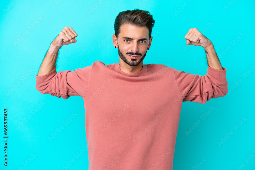 Young caucasian man isolated on blue background doing strong gesture Young caucasian man isolated on blue background doing strong gesture
