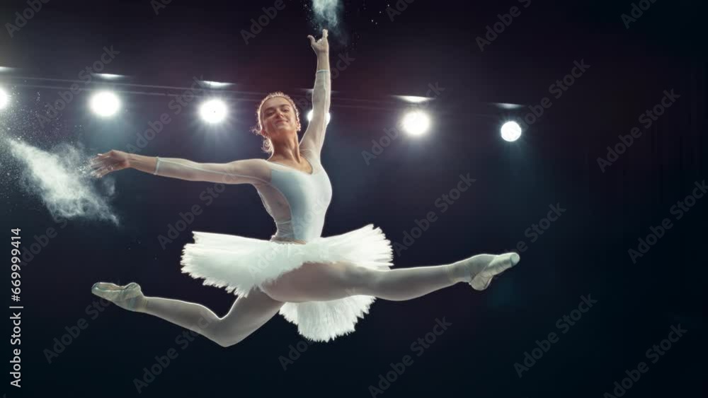Portrait of a Talented Ballet Dancer Performing on Stage. Young Female Making a Split Leap Jump and Releasing Powder From Her Hands in a Dark Studio. Cinematic Super Slow Motion Speed Ramp Footage Portrait of a Talented Ballet Dancer Performing on Stage. Young Female Making a Split Leap Jump and Releasing Powder From Her Hands in a Dark Studio. Cinematic Super Slow Motion Speed Ramp Footage