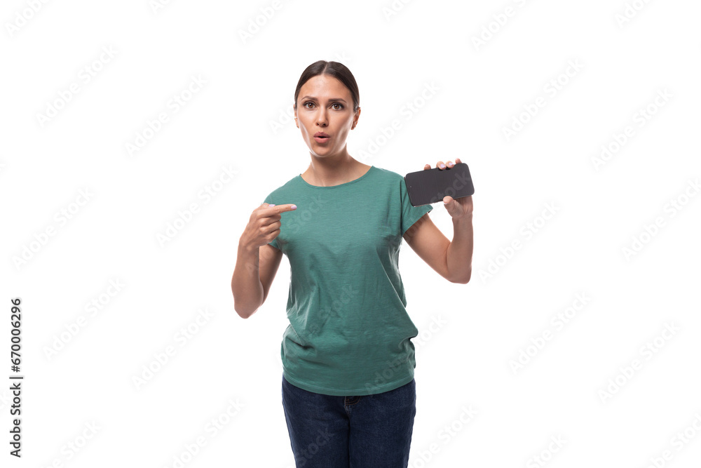 30 year old slender european brunette woman with a ponytail dressed in a green t-shirt and jeans shows the news on a smartphone screen 30 year old slender european brunette woman with a ponytail dressed in a green t-shirt and jeans shows the news on a smartphone screen