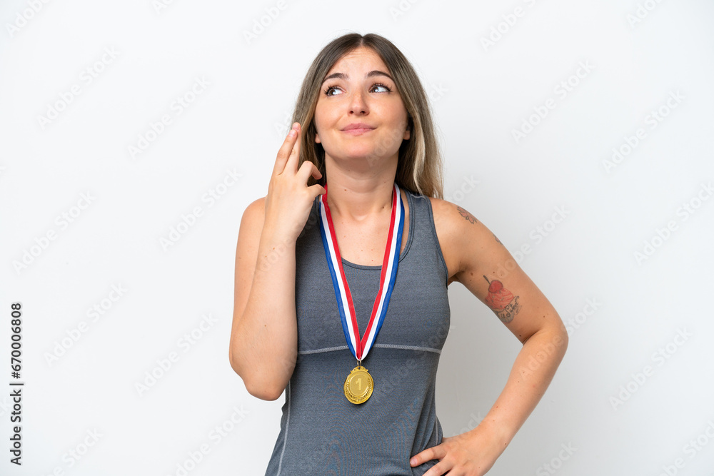 Young Rumanian woman with medals isolated on white background with fingers crossing and wishing the best Young Rumanian woman with medals isolated on white background with fingers crossing and wishing the best