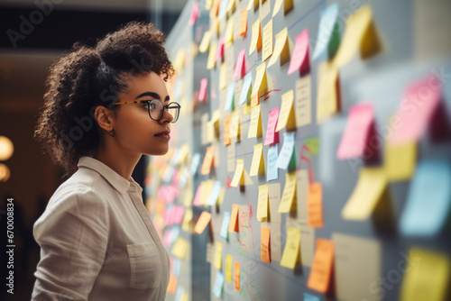 Portrait of Australian aboriginal woman picking up an idea note fro the board on searching the new project ideas