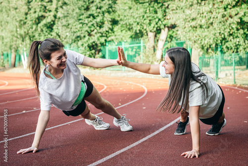 Young women doing stretching exercises at the stadium.